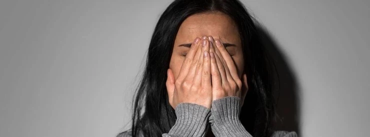 płacząca młoda kobieta zakrywa twarz dłońmi