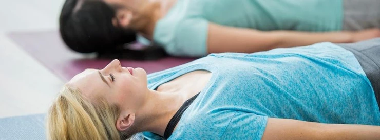 dwie kobiety leżące na macie do jogi z zamkniętymi oczami